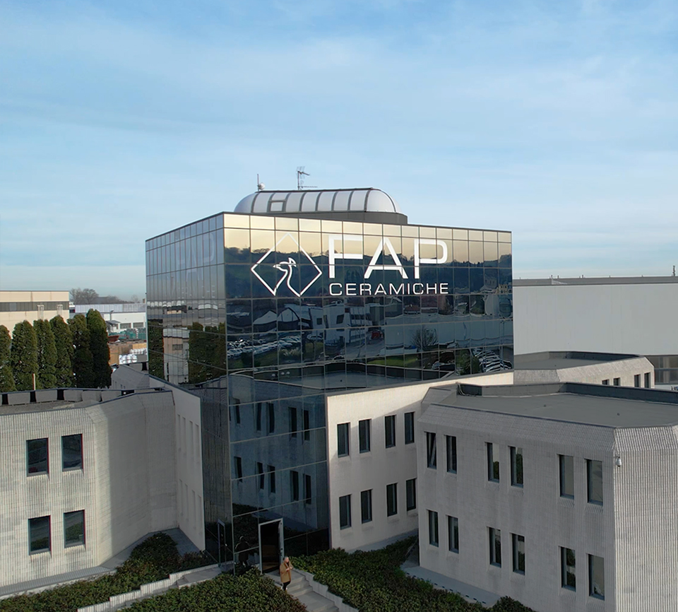 FAP Ceramiche headquarters with reflective glass façade and company logo, a modern building in light-coloured concrete with geometric architectural details.