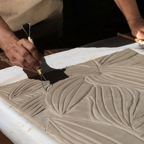 Piastrella decorata con maxi foglie tropicali in rilievo nei toni verde, rame e sabbia su fondo neutro, effetto naturale e avvolgente.