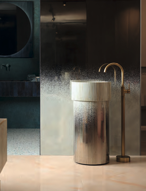 Freestanding marble-effect washbasin with gold tap, on a background with smoked mirror and light wood and deep green surfaces.