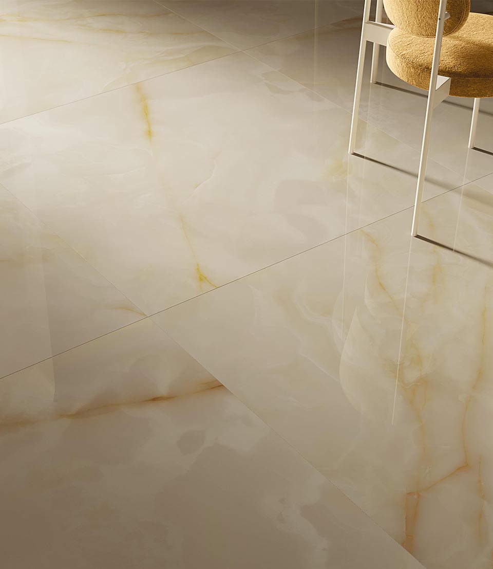 Detail of onyx-effect stoneware floor and wall tiles with gold veining combined with upholstered chair.