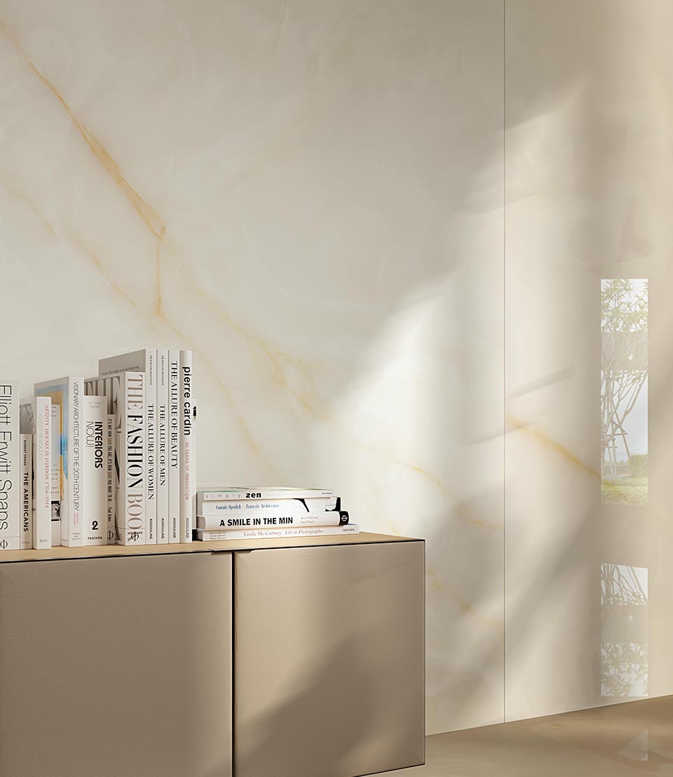 Onyx-effect porcelain stoneware wall tiles with gold veining, matt beige cupboard with books resting on it.