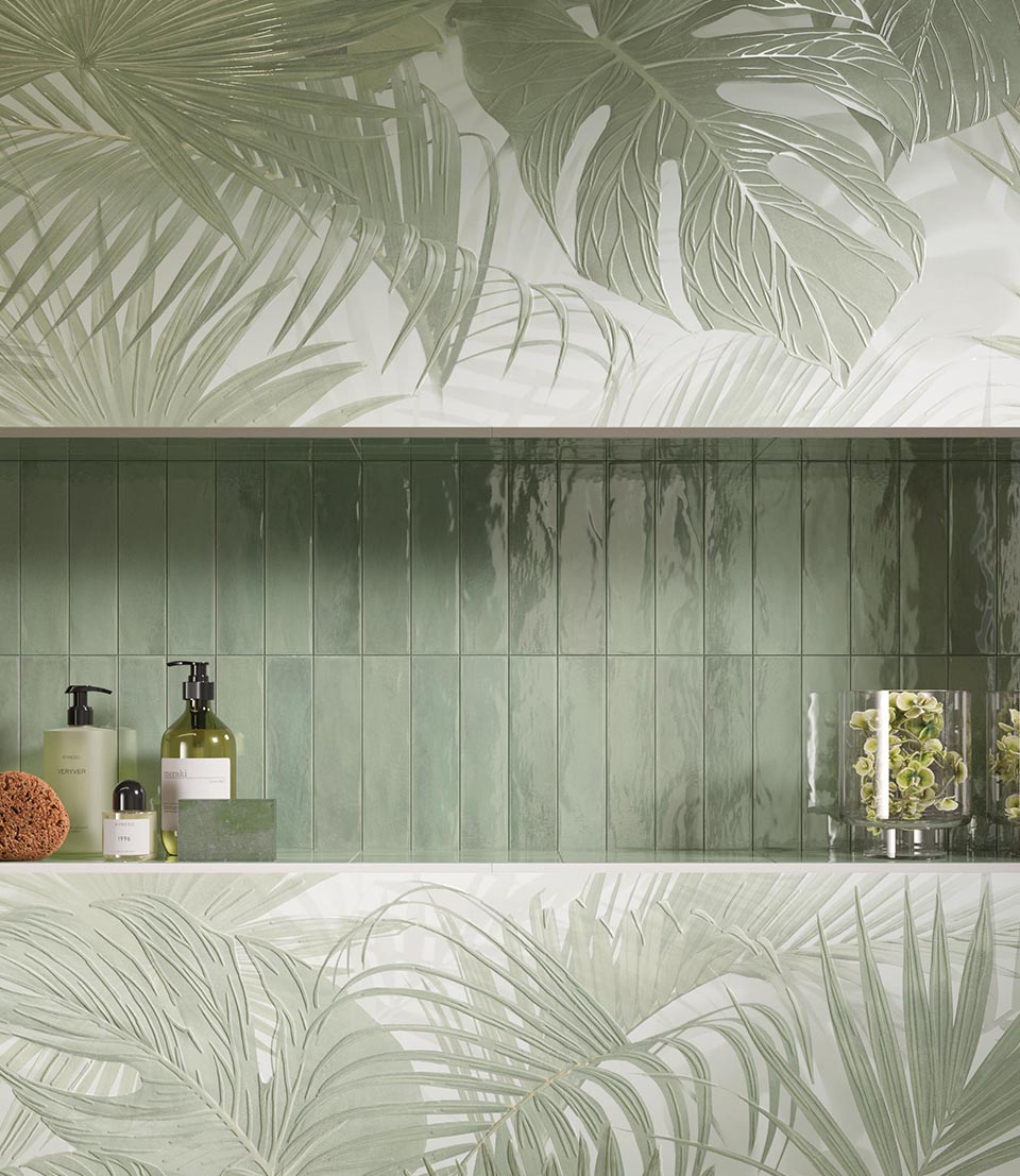 Sage green glossy brick-effect wall tiles with jungle relief insert and bathroom accessories; tropical ceramic composition in natural shades.
