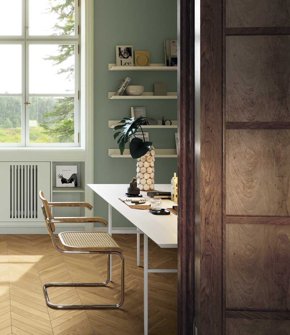 Study with light wood effect floor push, sage green walls, white desk and wood and metal chair, window to courtyard.