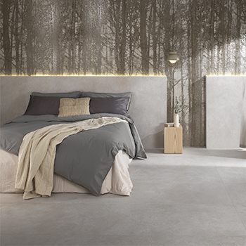 Modern bedroom with grey concrete-effect floor and walls, upholstered bed and backlit headboard with a dark-toned forest motif.
