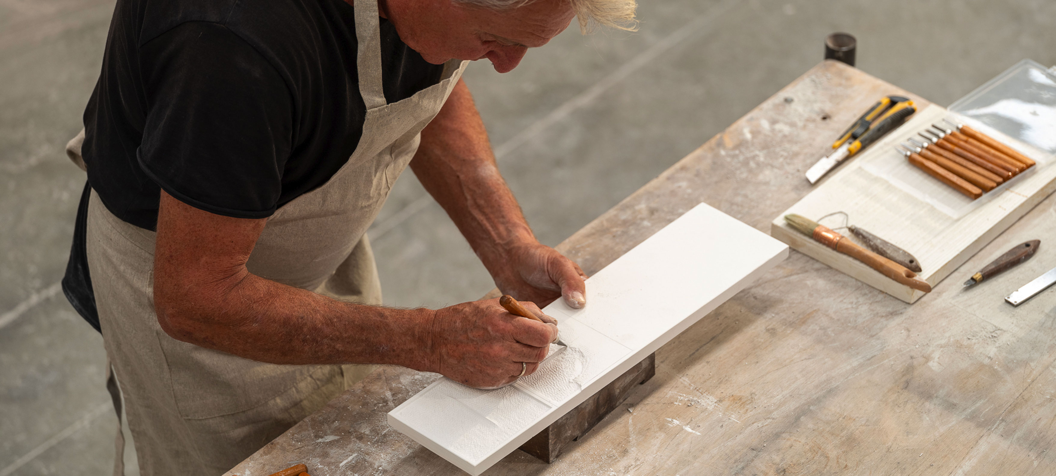 Hands working clay with spatula on rough surface, symbol of craftsmanship and material ceramic texture.