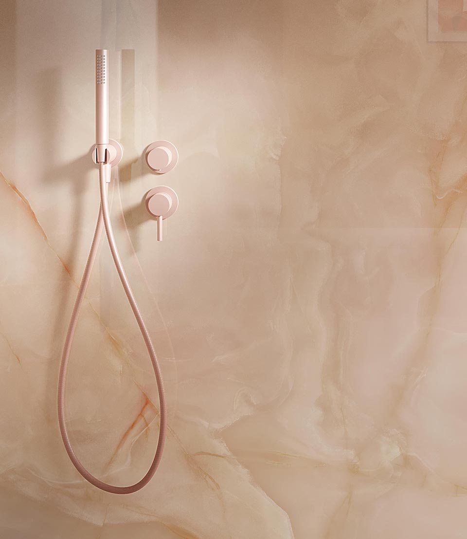 Detail of shower wall in glossy beige onyx-effect stoneware with orange veins and minimalist matt pink taps.