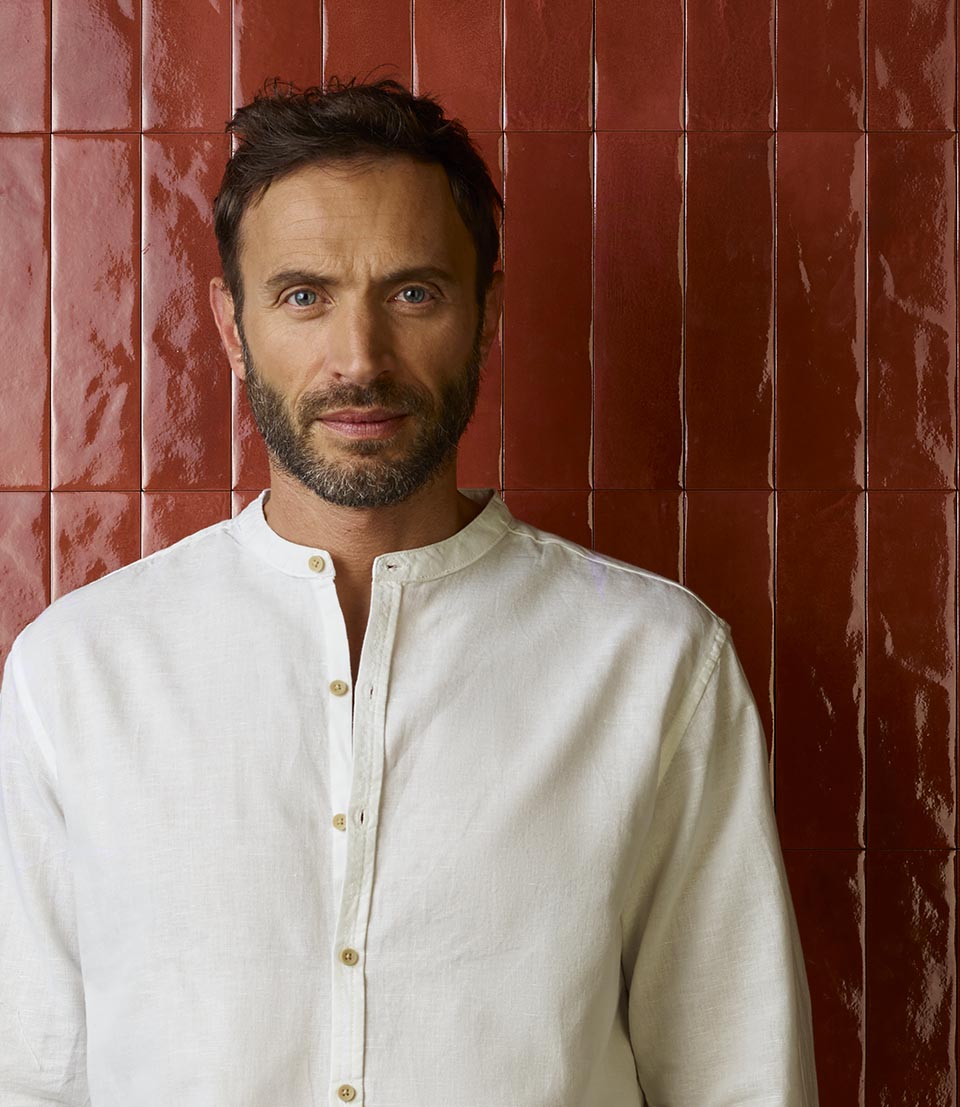Portrait of man in white shirt on red brick-effect tiling