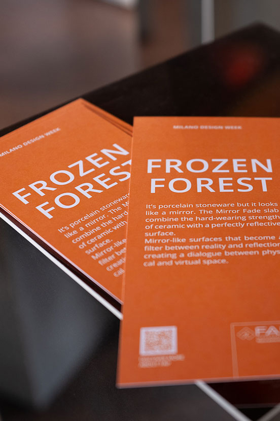 Dettaglio brochure arancione Frozen Forest con testo esplicativo su ceramica effetto specchio e superfici riflettenti.