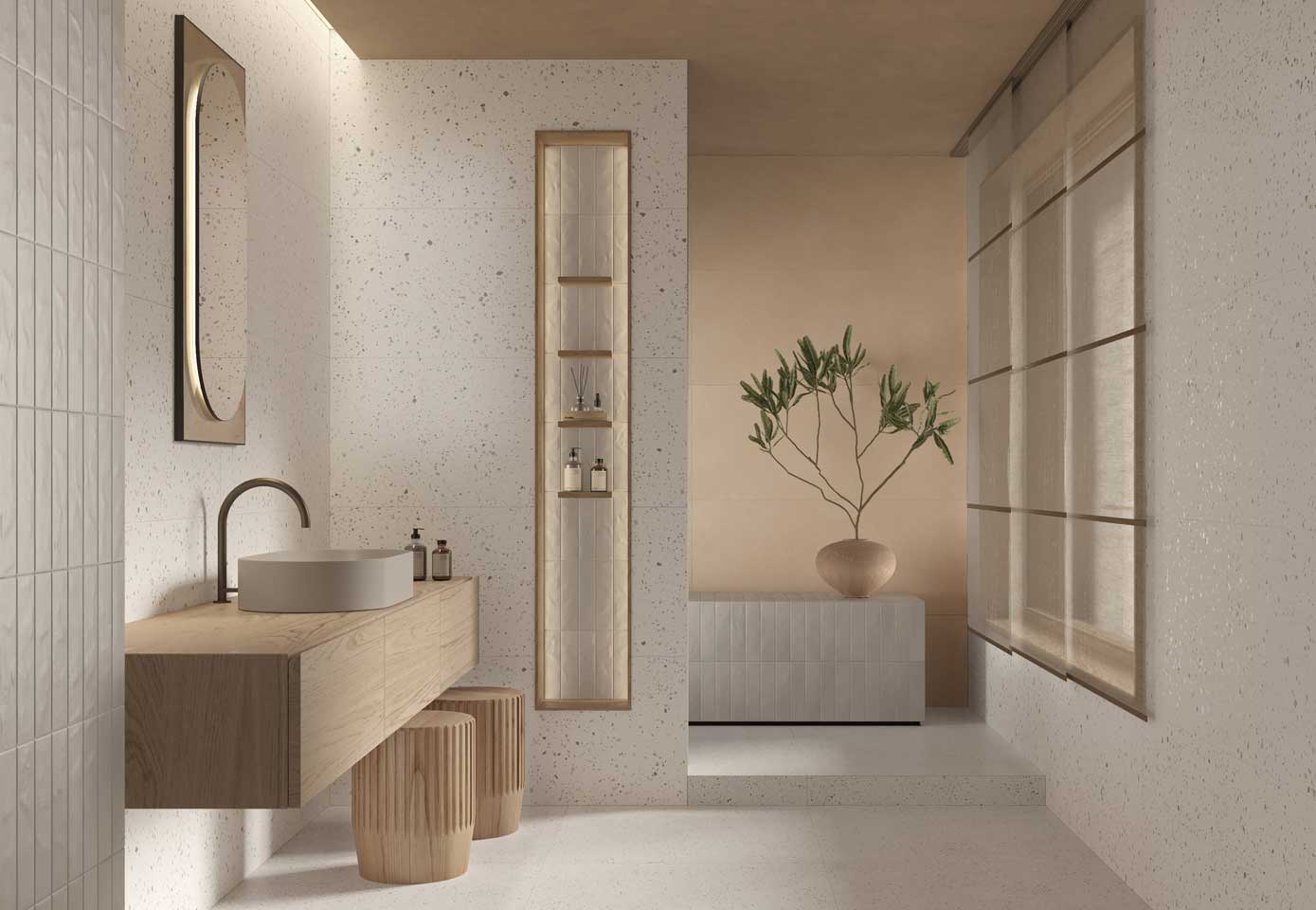 Bathroom with light terrazzo effect wall tiles, oval washbasin on wooden top and various striped ceramic objects, gray brick effect column.