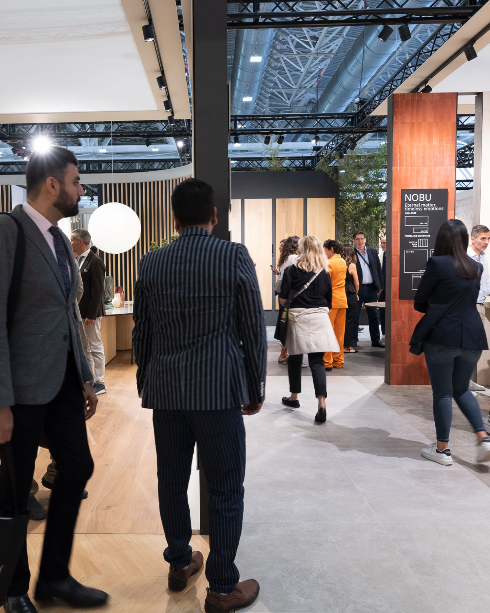 Visitors among the FAP Ceramiche stands, grey stoneware and light wood flooring, decorative panels and contemporary design furnishings.