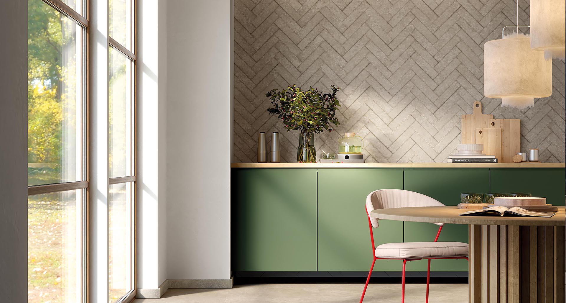 Kitchen with beige stoneware tiled wall, sage green kitchen base, light wood round table, white fabric chair, large windows.