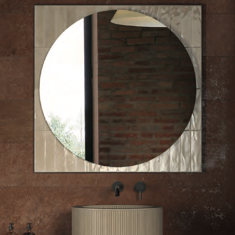 Round mirror with glossy white frame on a red brick-effect wall. Pedestal washbasin and matt black tap.