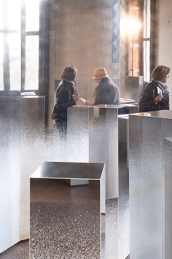 Visitatori tra totem ceramici riflettenti con sfumature bianche, interni luminosi e atmosfera immersiva Frozen Forest.