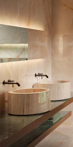 Detalle de baño moderno con alicatados efecto ónix rosa y lavabos de cerámica estriada rosa, grifería negra.