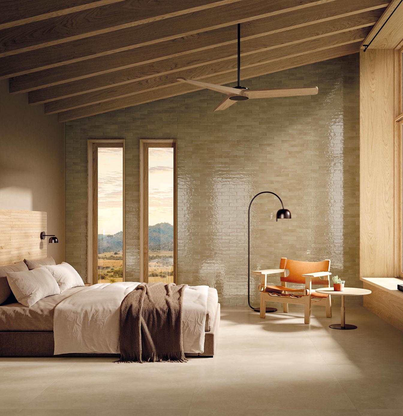 Room with polished taupe tiled wall, exposed wooden beams, minimal bed and reading area with armchair and floor light