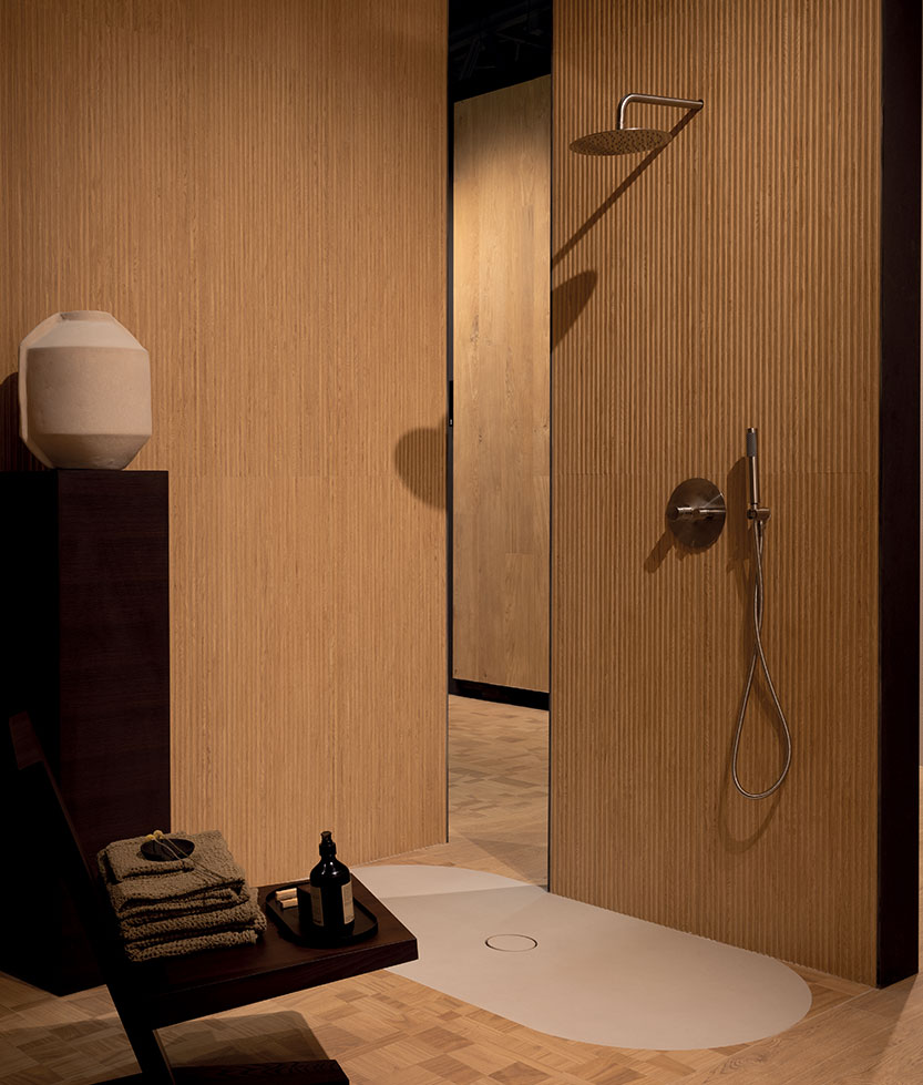 Shower enclosure with light wood-effect vertical slatted cladding, white shower tray and satin steel taps.