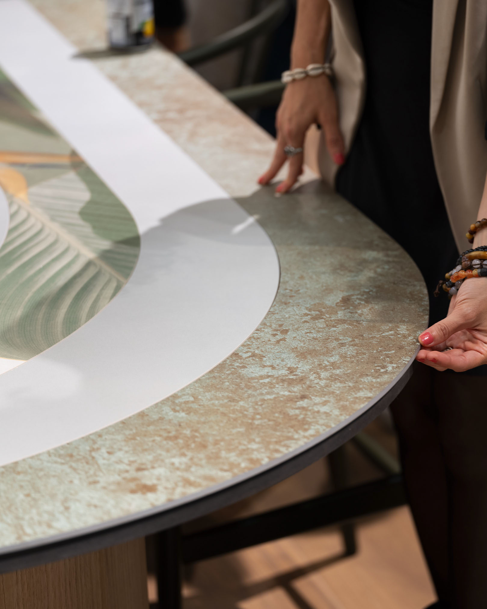 Detail of a stoneware table top decorated with a textured effect, hands highlighting the surface and modern graphic patterns.