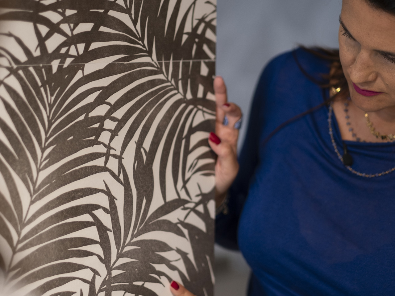 Dettaglio rivestimento FAP con pattern foglie nere su fondo chiaro, mostrato in showroom con focus su texture e decoro.