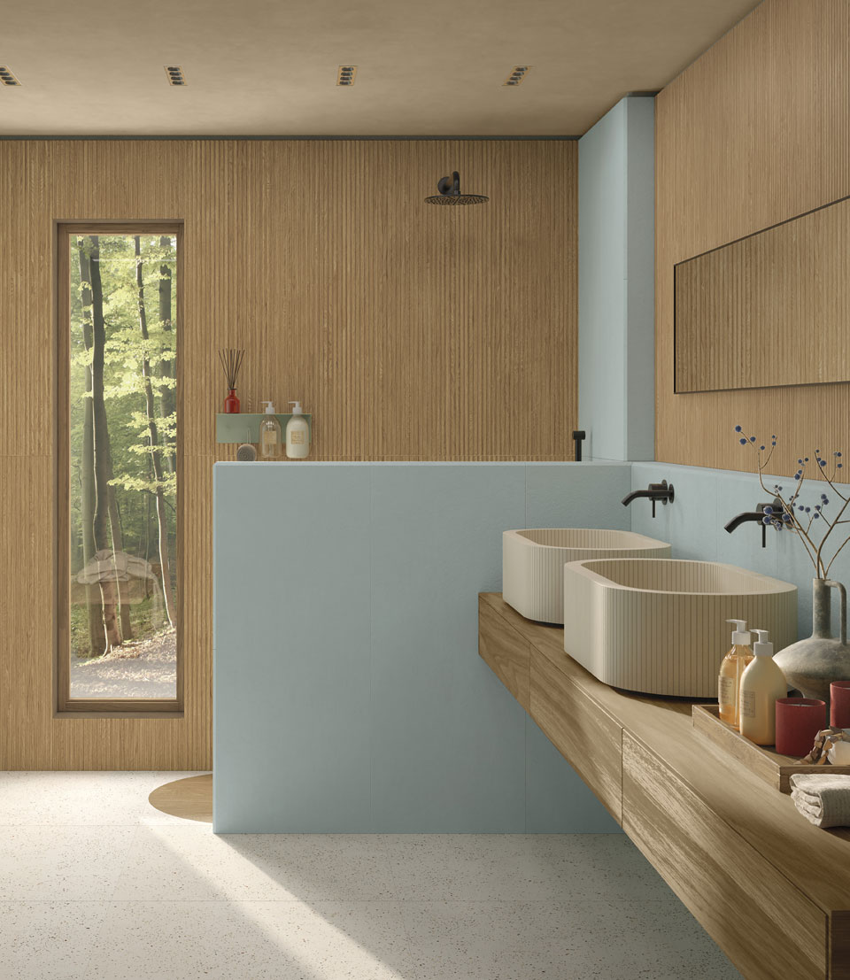 Modern bathroom with wood-effect slatted walls, matte blue wall tiles, double wall-hung top washbasin in wood-effect stoneware, terrazzo-effect stoneware floor.