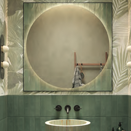 Backlit mirror with glossy green frame on a decorated tropical wall. Striped washbasin, matt black taps.