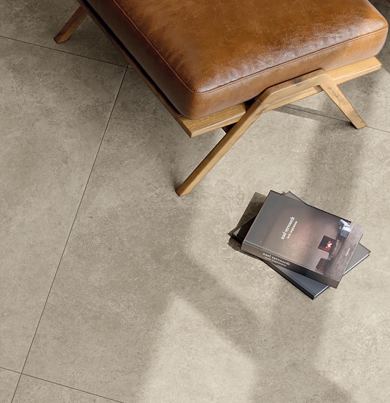 Beige stone-effect floor detail, leather pouf and interior books resting on the floor.