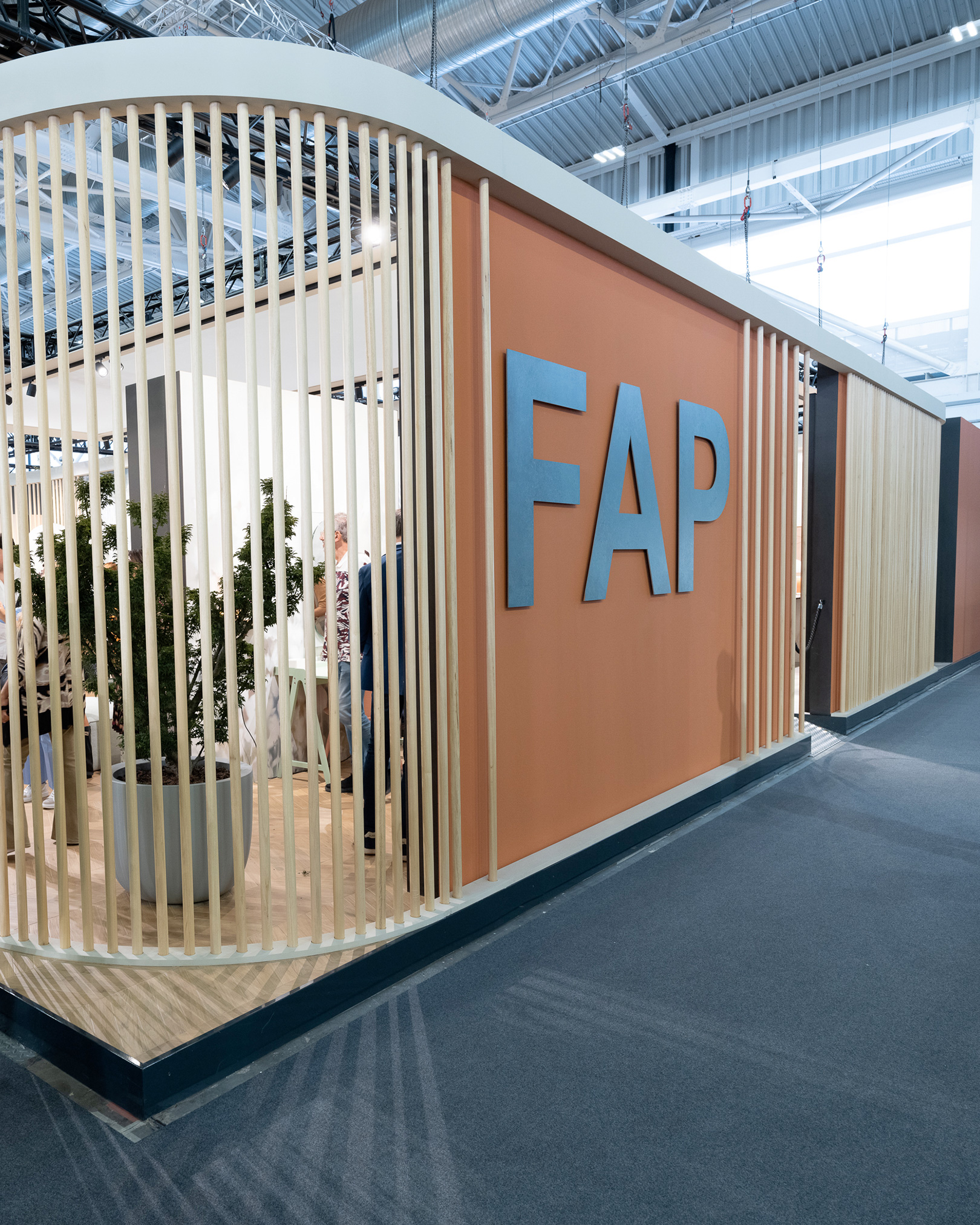 Cersaie FAP Ceramiche stand with orange walls, blue logo and vertical wooden slatted structure creating a modern and welcoming design.