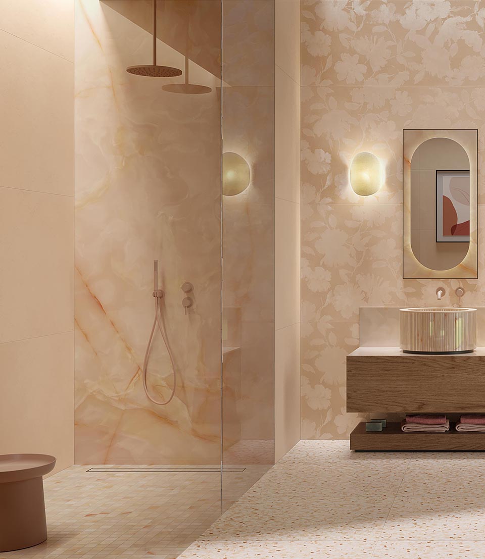 Bathroom with shower and walls covered in glossy beige onyx, cylindrical washbasin on wooden cabinet and tone-on-tone floral details.