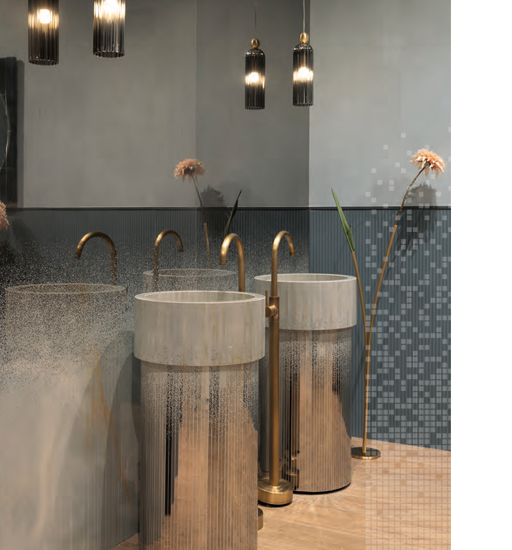 Double mirror-effect grooved washbasin with brass taps, blue stoneware wall coverings and decorative lighting.