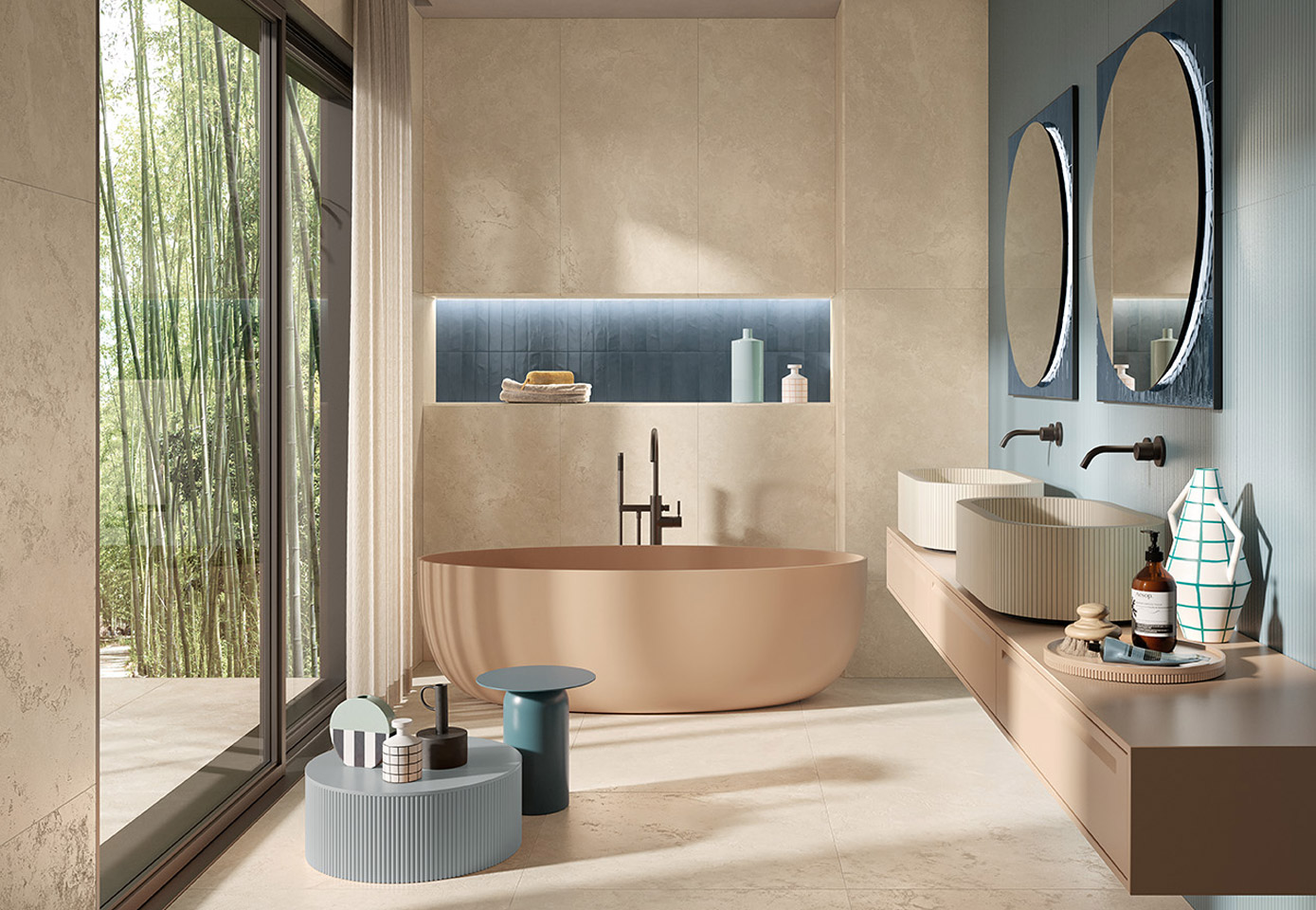 Bathroom with powder pink freestanding bathtub, decorative washbasins and matt beige and blue stoneware walls, double round mirror, light stone effect stoneware floor, large side window.