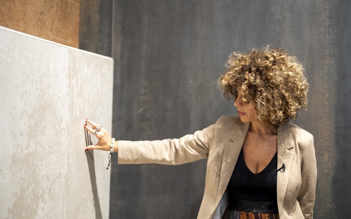 Designer osserva piastrella effetto cemento nei toni beige e antracite, texture materica e superfici dal look industriale.