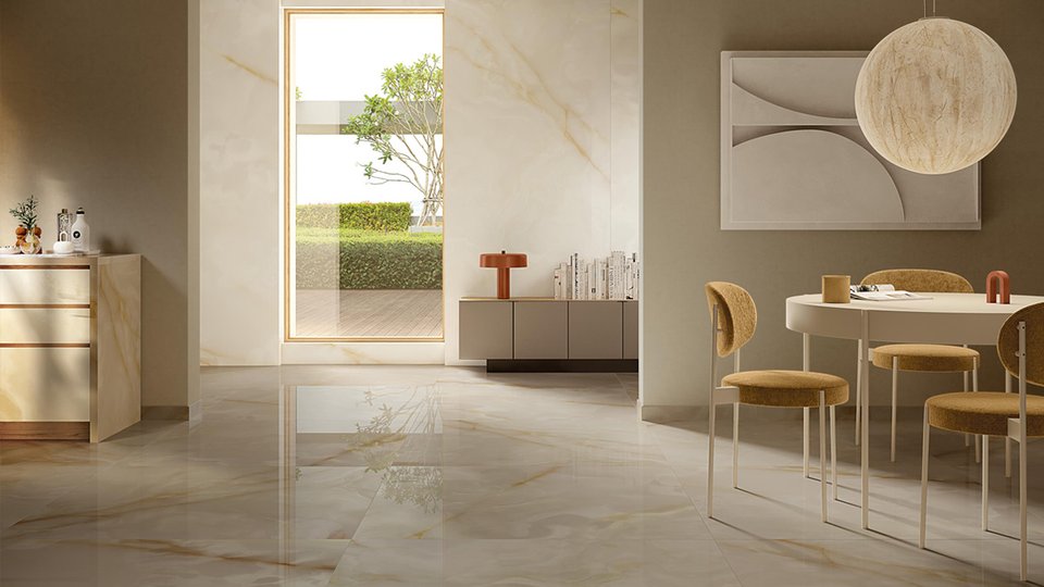 Living area with light marble-effect flooring and beige and ochre furnishings, illuminated by large windows and natural light.