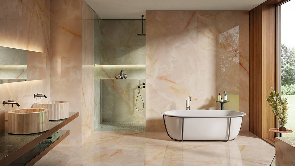 Refined bathroom with glossy pink onyx effect wall tiles, double cylindrical washbasins and white freestanding bathtub.