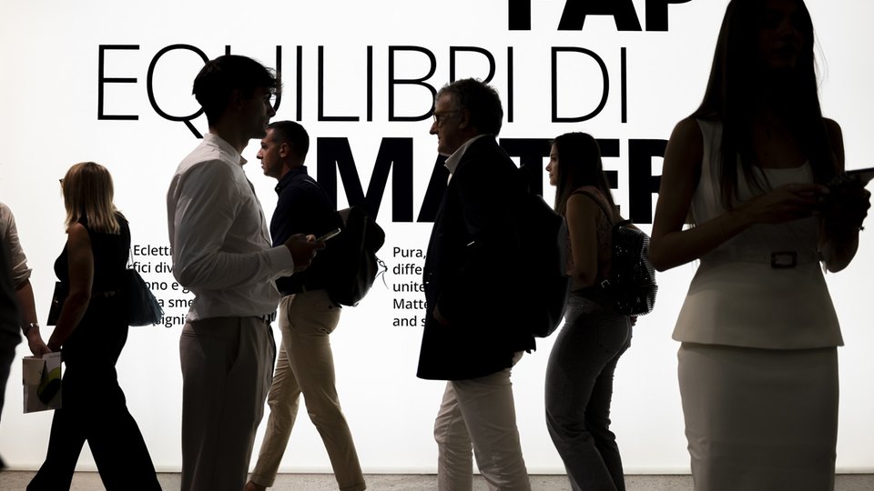 Persone durante evento FAP Ceramiche davanti alla scritta “Equilibri di Materia”, in uno spazio espositivo luminoso e moderno.