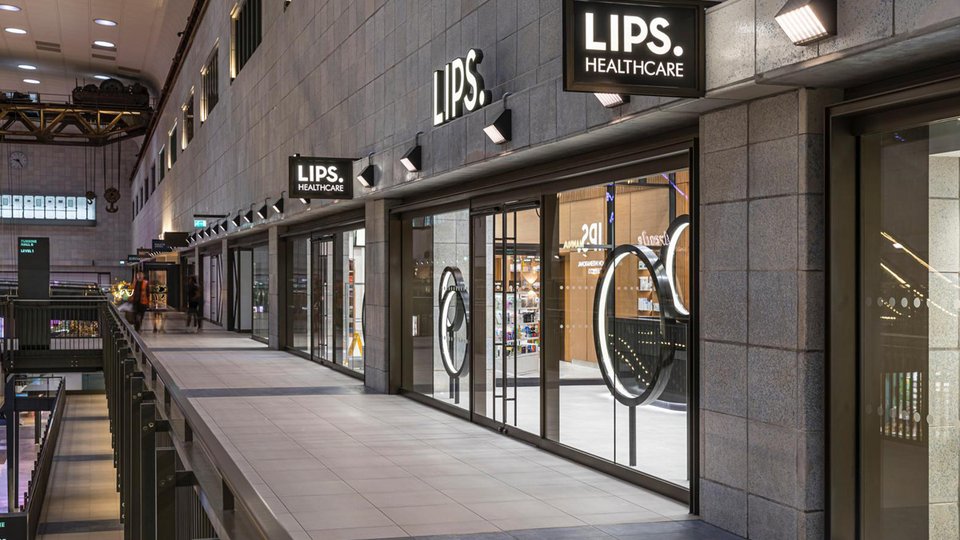 Modern façade with grey stone-effect cladding, illuminated display windows and minimalist LIPS Healthcare signage.
