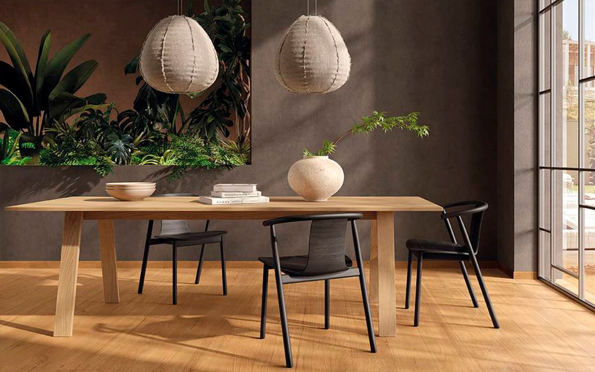 Modern dining area with light wood-effect flooring, mud-colored walls, and a large oak table, decorated with tropical plants.