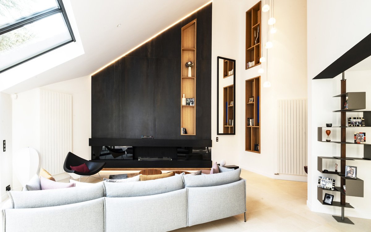 Contemporary living room with white walls and dark paneling, gray sofa, and bright details for an elegant, minimalist design.
